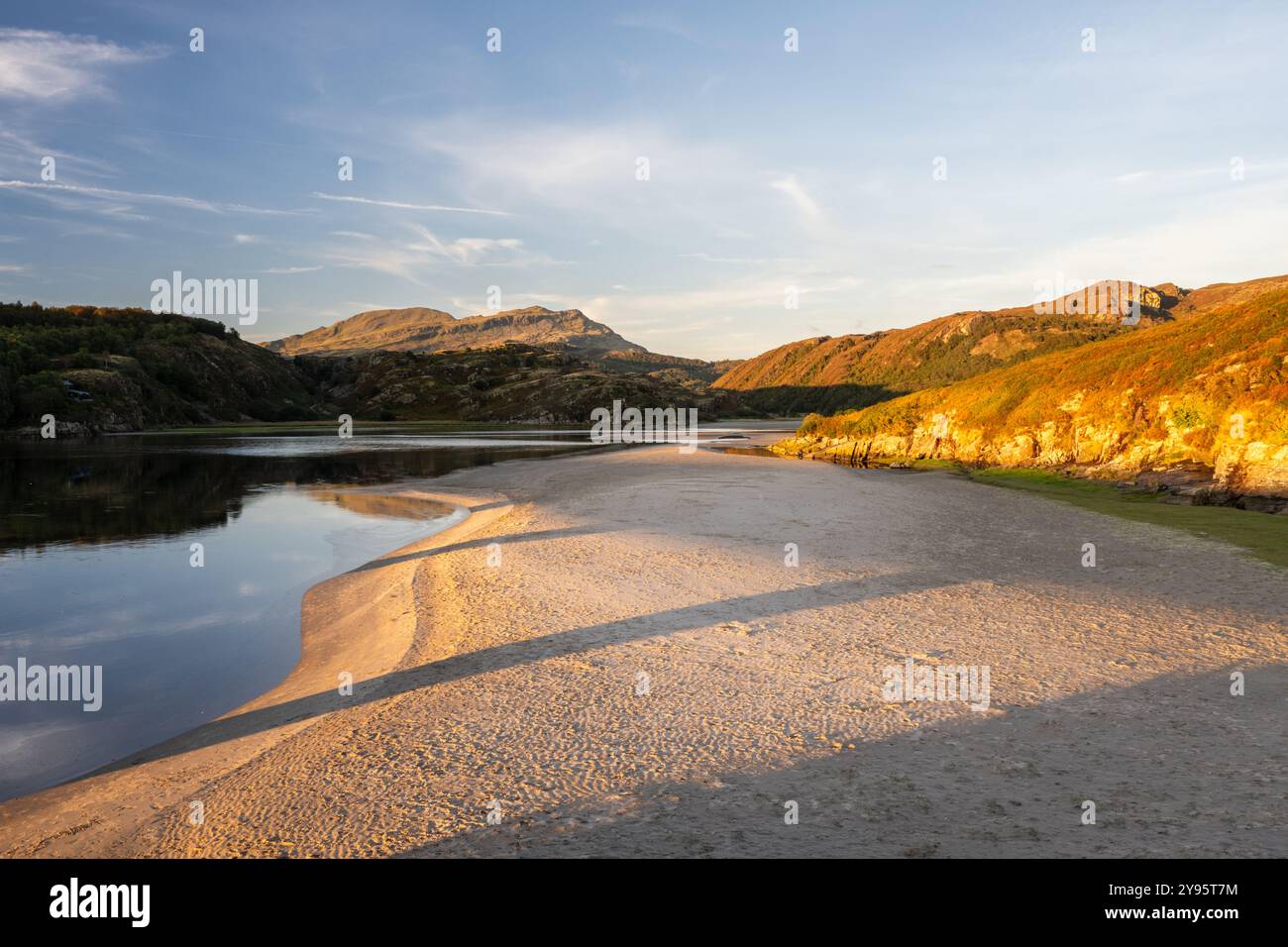 La luce della sera splende sulle rive sabbiose dell'estuario del fiume Afon Dwyryd sotto le colline di Snowdonia nel Galles del Nord. Foto Stock