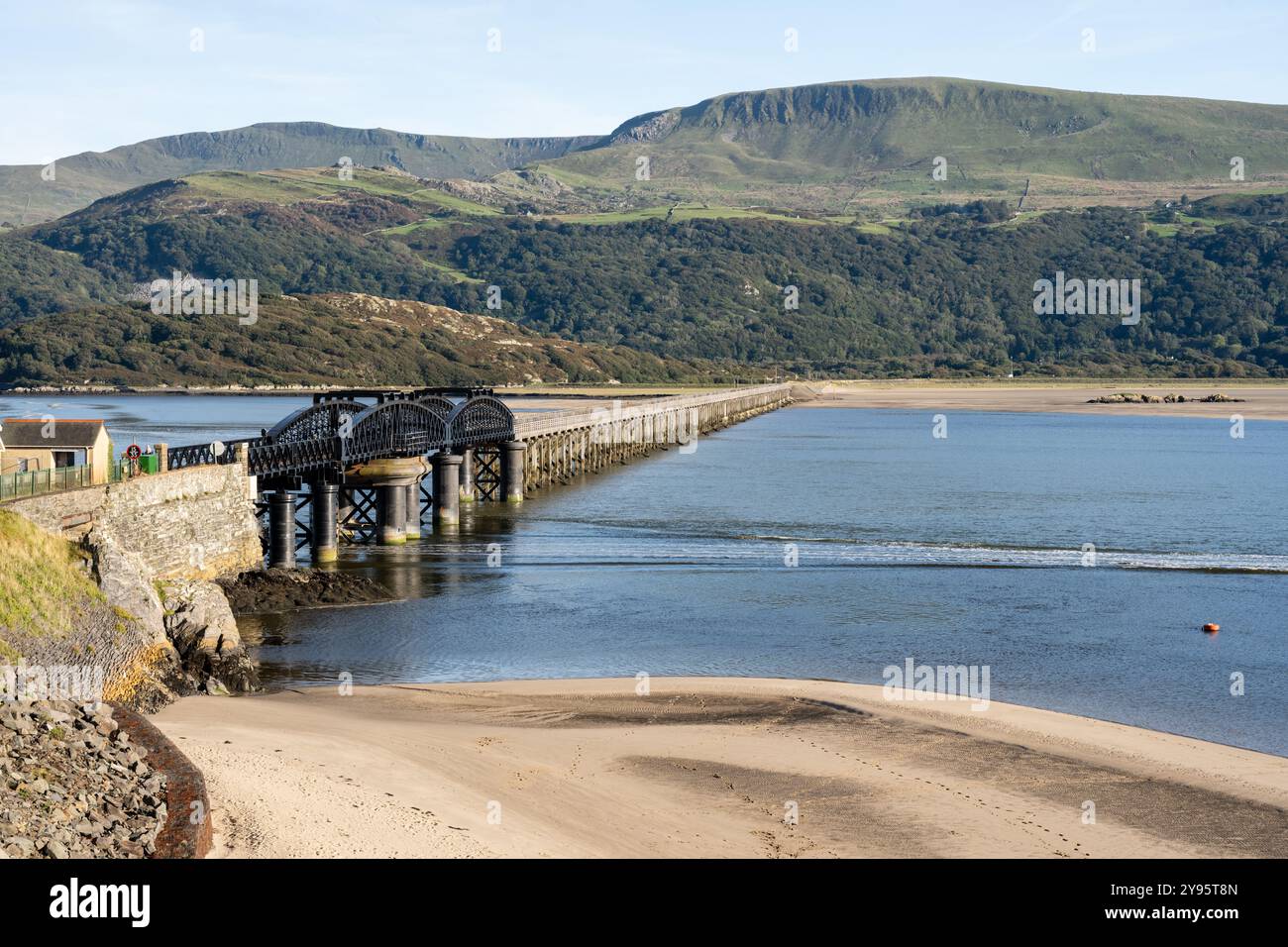 Il viadotto di Barmouth Bridge attraversa l'estuario di Mawddach sotto le colline del Parco Nazionale di Snowdonia nel Galles del Nord. Foto Stock