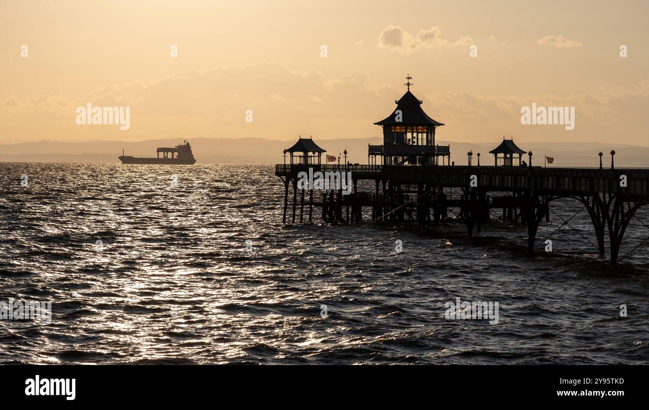 Una nave da carico viaggia lungo il Canale di Bristol al tramonto, dietro il molo di Clevedon nel Somerset. Foto Stock