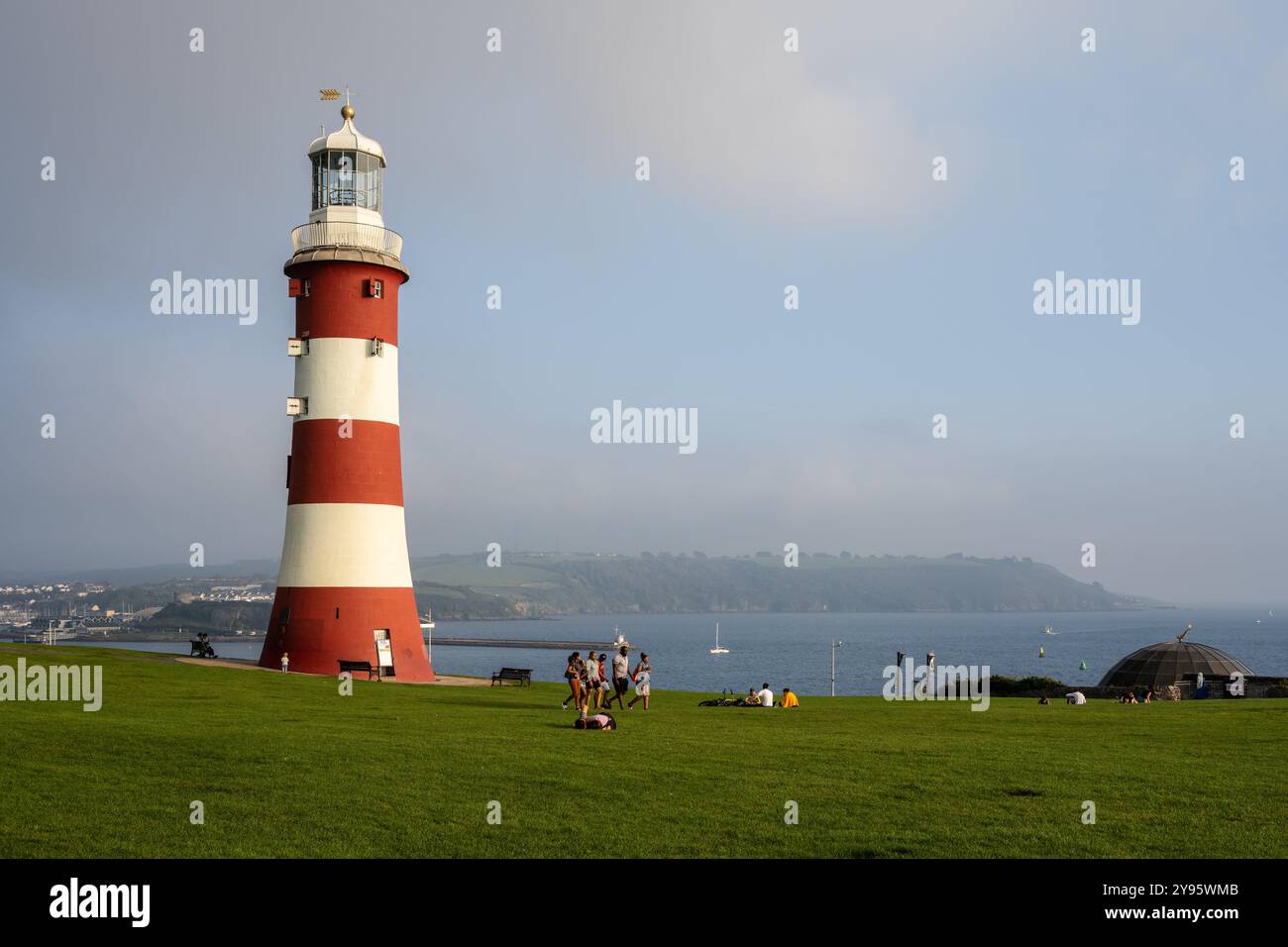 La gente passa davanti al faro della Torre di Smeaton nel parco Plymouth Hoe nel Devon. Foto Stock