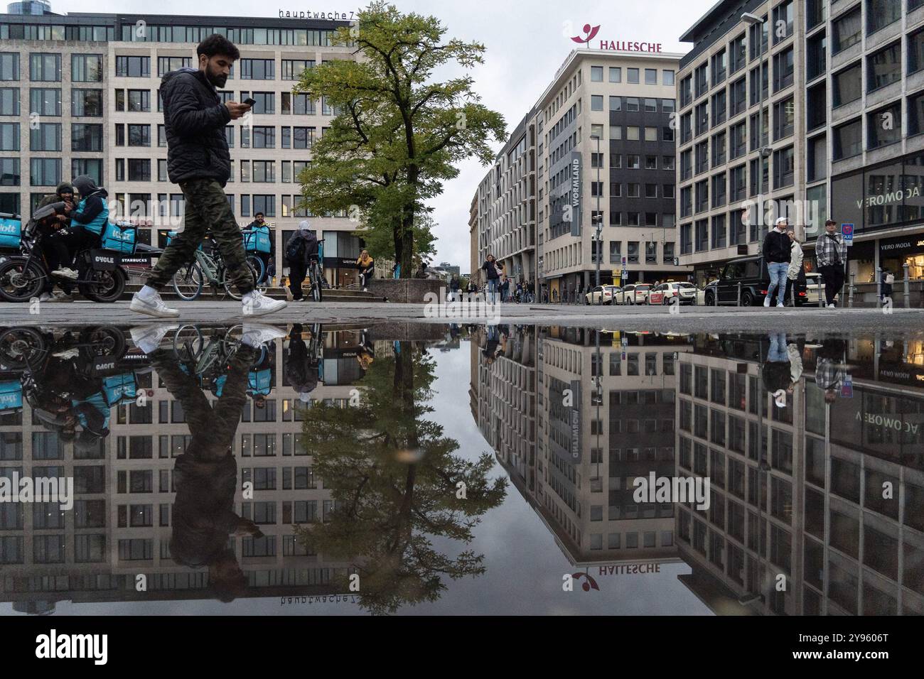 Magonza, Renania Palatinato, Germania. 8 ottobre 2024. Le persone si riflettono in una pozza d'acqua dopo una giornata di pioggia a Francoforte, in Germania. (Immagine di credito: © Matias Basualdo/ZUMA Press Wire) SOLO PER USO EDITORIALE! Non per USO commerciale! Foto Stock