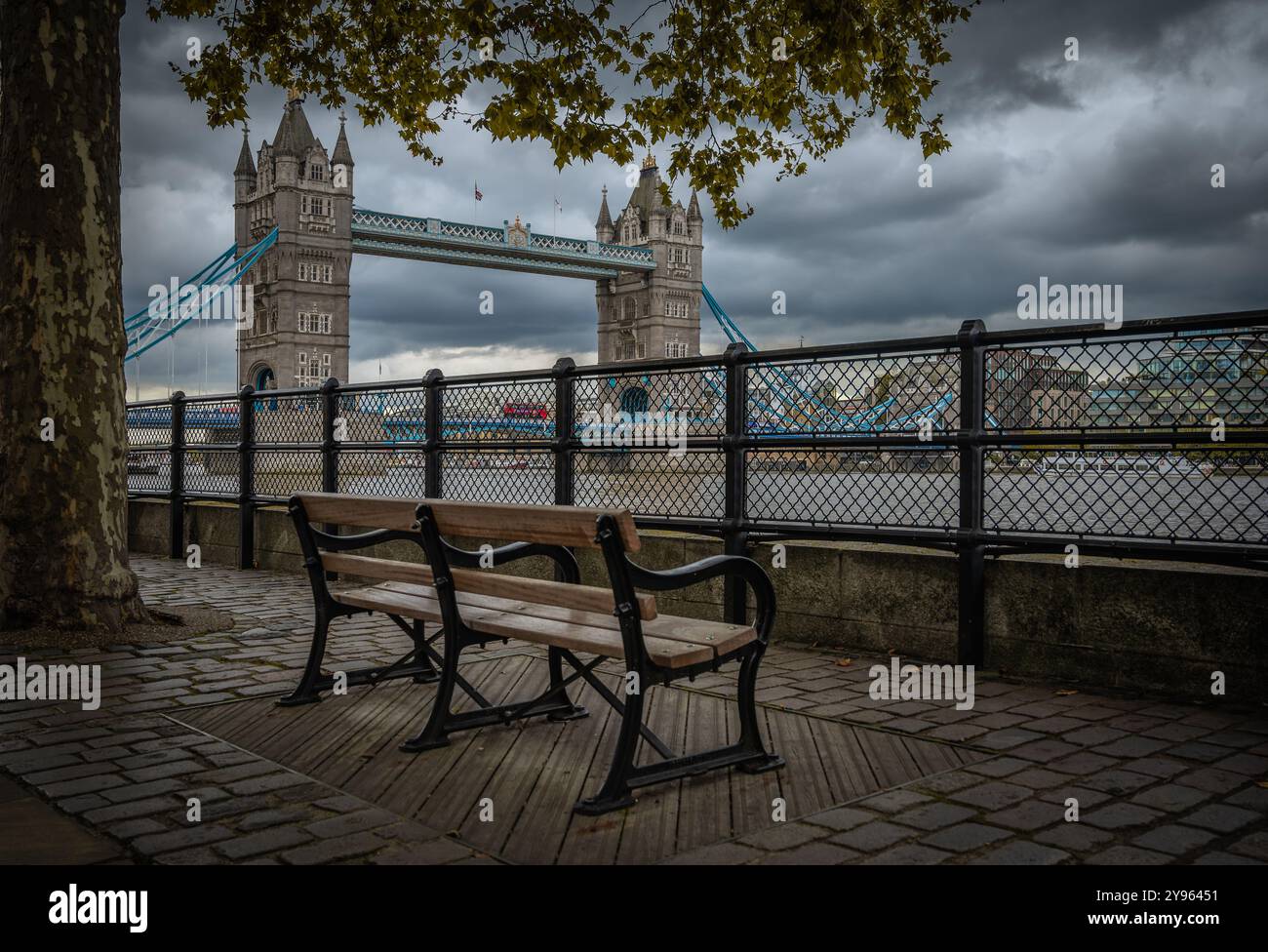 Tower Bridge a Londra in un giorno nuvoloso con una panchina del parco sulla riva del Tamigi Foto Stock