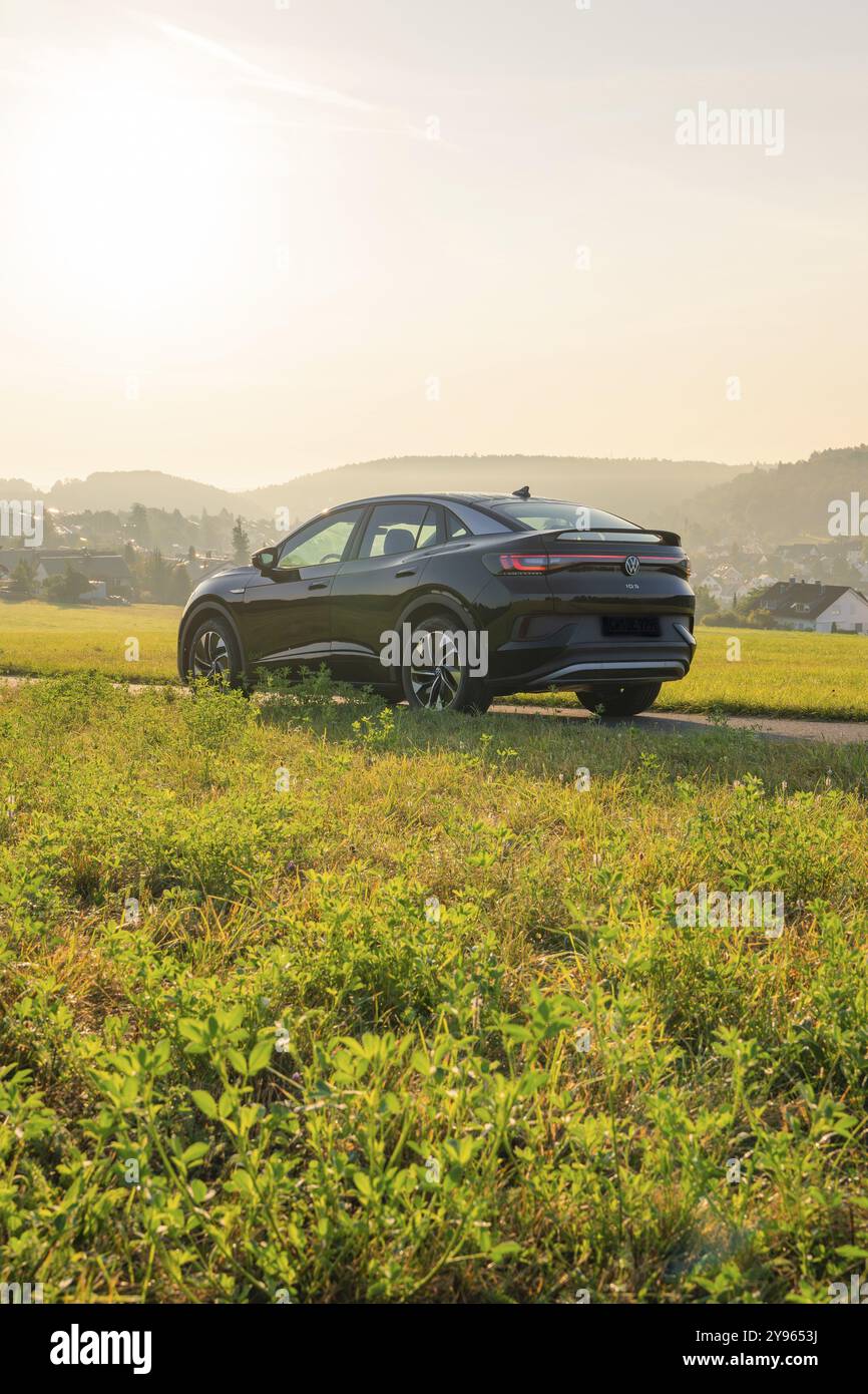 SUV su una strada rurale con vista sulle colline sullo sfondo, al tramonto, auto elettrica VW ID5, Calw, Foresta Nera, Germania, Europa Foto Stock