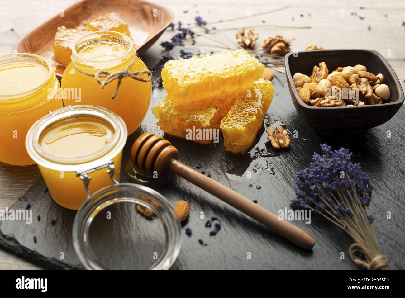 Nido d'ape su vassoio in ardesia con miele e noci sul tavolo della cucina, fotografia di cibo, fotografia di cibo Foto Stock