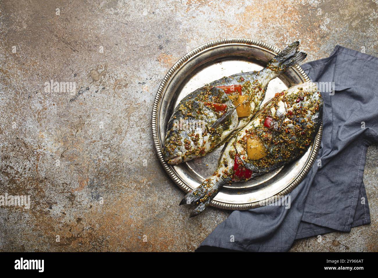 Due pesci crudi dorado farciti con verdure e condimenti pronti per essere cucinati posando su piatto di metallo rustico su vecchio vassoio forno vista dall'alto, spazio per il testo Foto Stock