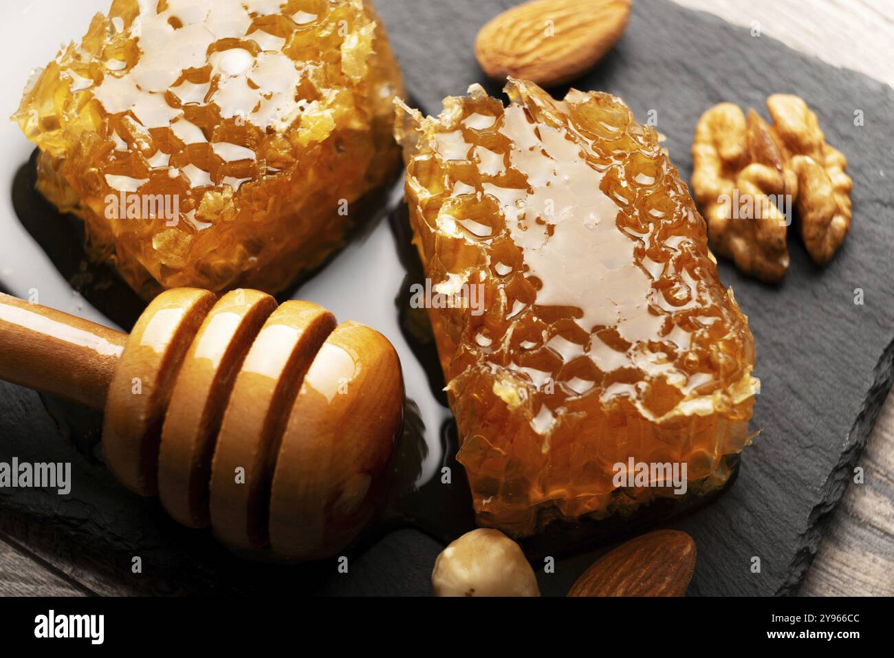 Nido d'ape su vassoio in ardesia con miele e noci sul tavolo della cucina, fotografia di cibo, fotografia di cibo Foto Stock