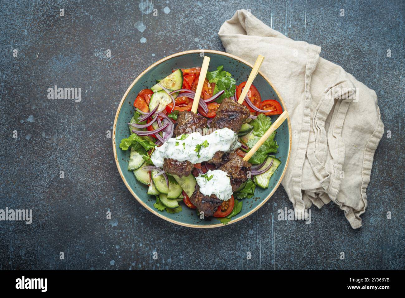 Spiedini grigliati di carne di manzo spiedini su bastoncini serviti con insalata di verdure fresche su piatto su sfondo rustico di cemento dall'alto. EAS centrale tradizionale Foto Stock