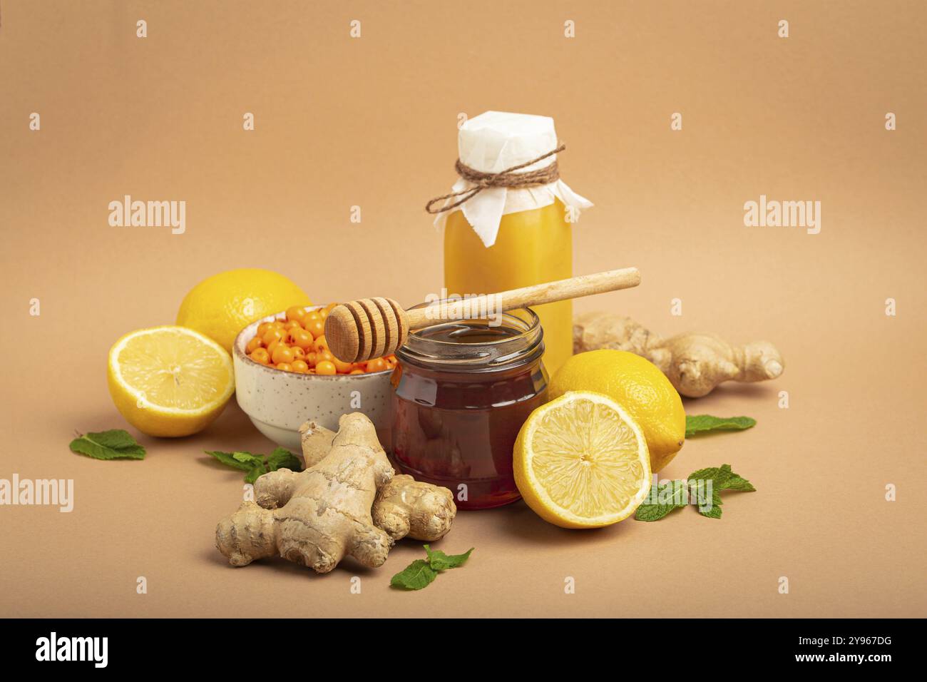 Composizione con bevanda disintossicante, frutti di bosco spinoso, limoni, menta, zenzero, miele in vaso di vetro. Cibo per la stimolazione immunitaria e contro l'influenza. In salute Foto Stock