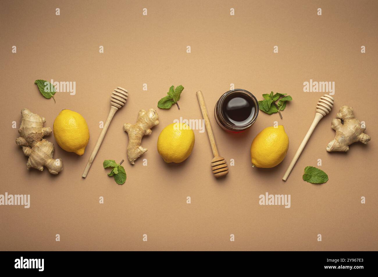 Composizione con limoni, menta, zenzero, miele in vaso di vetro e miele in legno a immersione vista dall'alto. Cibo per la stimolazione immunitaria e contro l'influenza stagionale. H Foto Stock