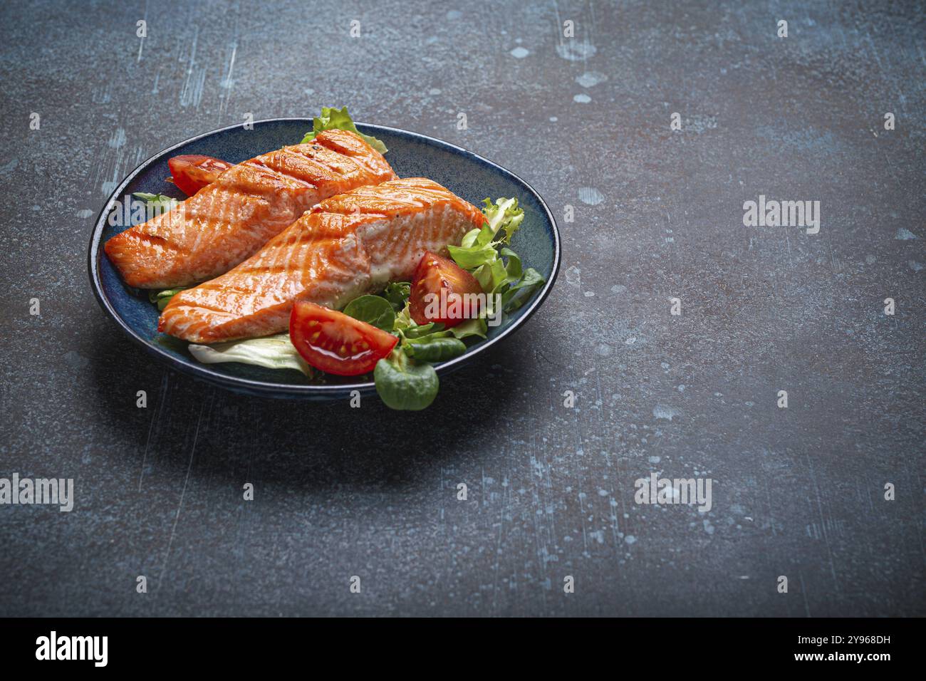 Carne di salmone alla griglia con insalata di verdure su piatto di ceramica su sfondo rustico, vista angolare, dieta bilanciata o pasto di insalata nutrizionale sana Foto Stock