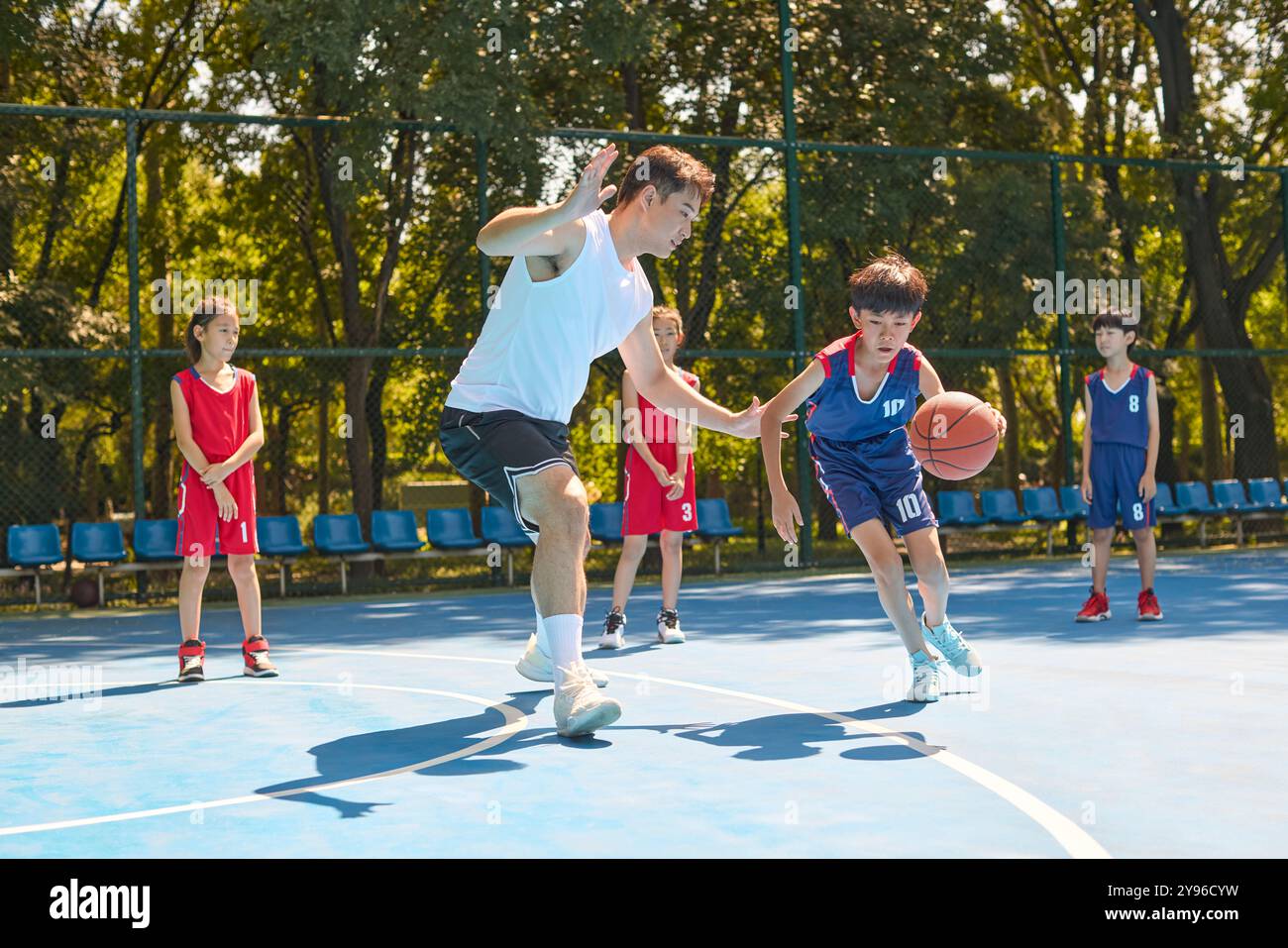 Coach che insegna ai bambini come giocare a basket Foto Stock