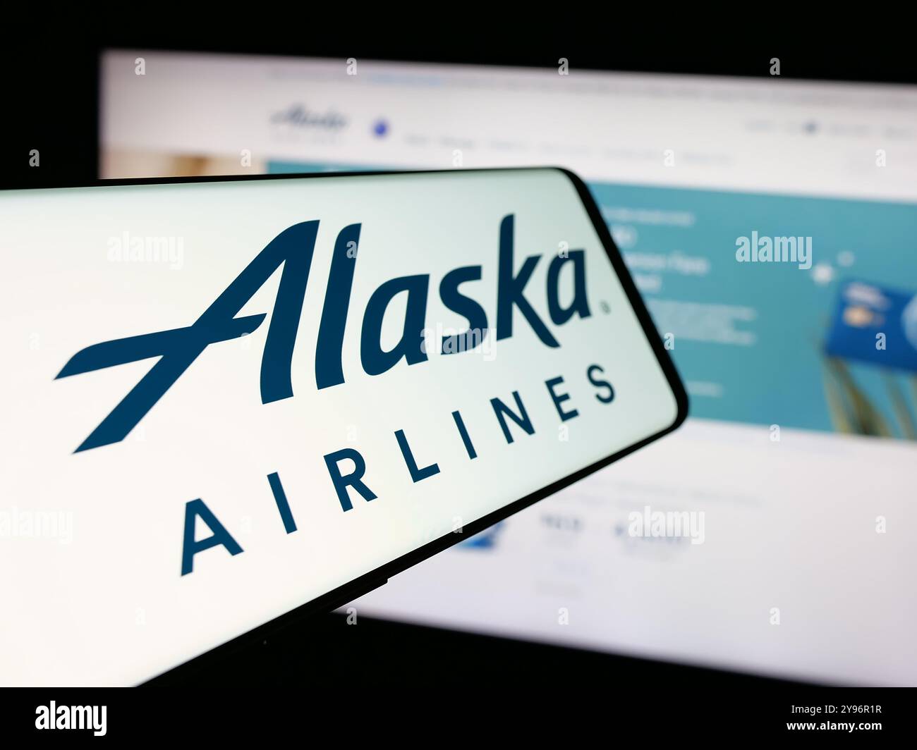 Cellulare con logo della compagnia aerea americana Alaska Air Group Inc. Sullo schermo davanti al sito Web. Mettere a fuoco la parte centrale sinistra del display del telefono. Foto Stock