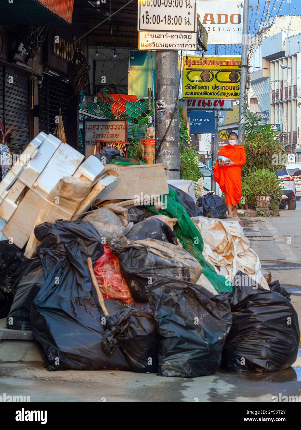 Un monaco visto camminare tra pile di rifiuti lungo la strada, gettato dai residenti dopo che le acque si sono ritirate. Dopo che la situazione delle inondazioni a Chiang mai si placò, i monaci di vari templi locali ripresero la loro elemosina, come al solito, in una città piena di rifiuti di oggetti danneggiati dalle inondazioni, fango e polvere dai sedimenti lasciati dietro dalle acque in ritirata. Sebbene le autorità governative e i residenti abbiano iniziato a pulire l'area e a rimuovere i detriti, molti punti sono ancora coperti di fango e polvere accumulati. Ci vorranno diverse settimane prima che la situazione torni alla normalità. Foto Stock