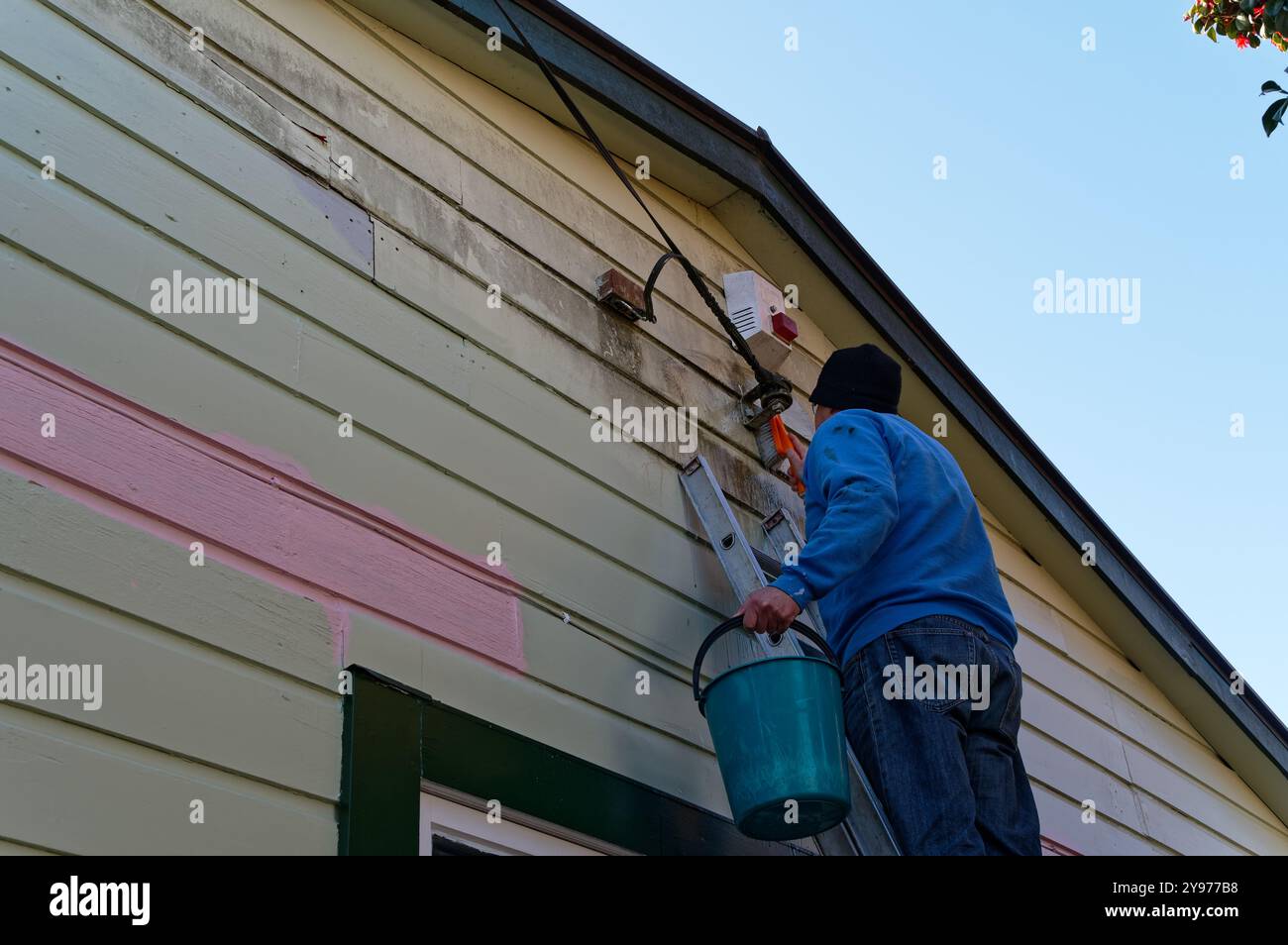 Tempo per dipingere la casa, la preparazione è in corso, pulire le tavole meteorologiche prima della verniciatura. L'alimentazione è stata disattivata poiché la linea deve essere cle Foto Stock