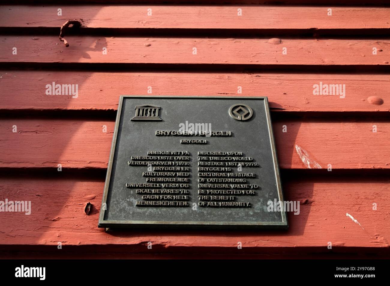 Targa patrimonio dell'umanità dell'UNESCO su un tradizionale edificio in legno presso il molo anseatico di Bryggen, Bergen, Norvegia. Foto Stock