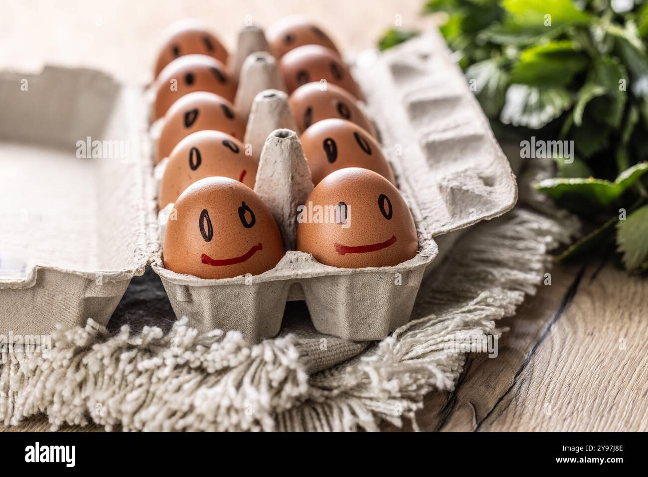 Le uova fresche sorridono in un cartone di carta sul tavolo della cucina. Foto Stock