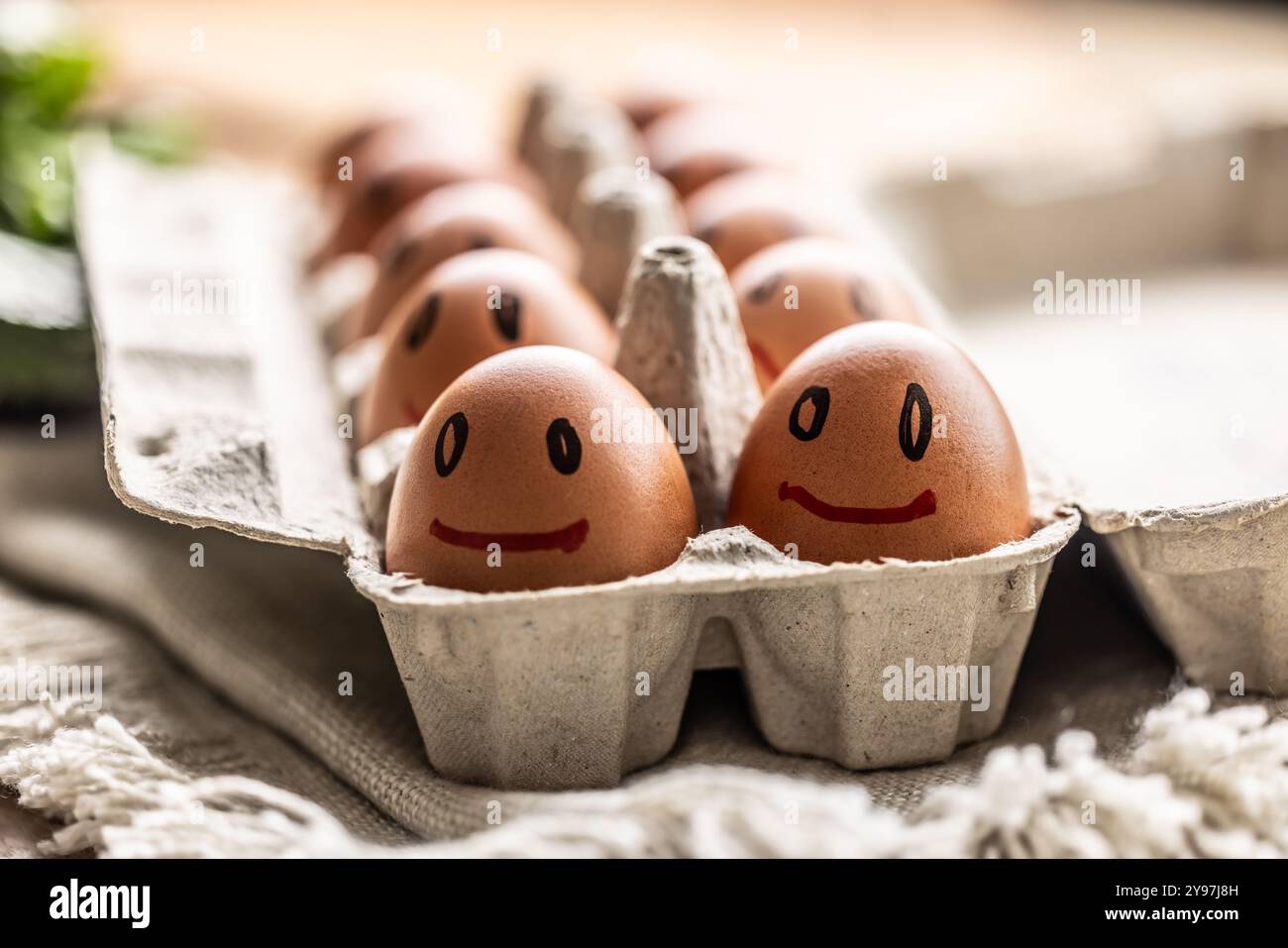 Le uova fresche sorridono in un cartone di carta sul tavolo della cucina. Foto Stock