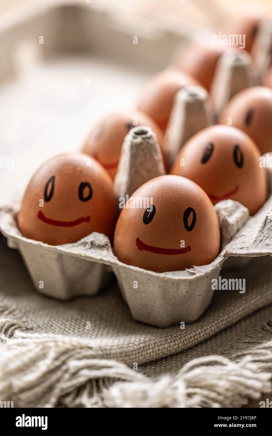 Le uova fresche sorridono in un cartone di carta sul tavolo della cucina. Foto Stock