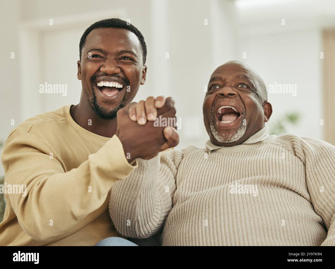 Famiglia nera felice, tenersi per mano e guardare la tv con entusiasmo per commedie, film o serie a casa. Uomini africani, tifosi e tifosi per festeggiare Foto Stock