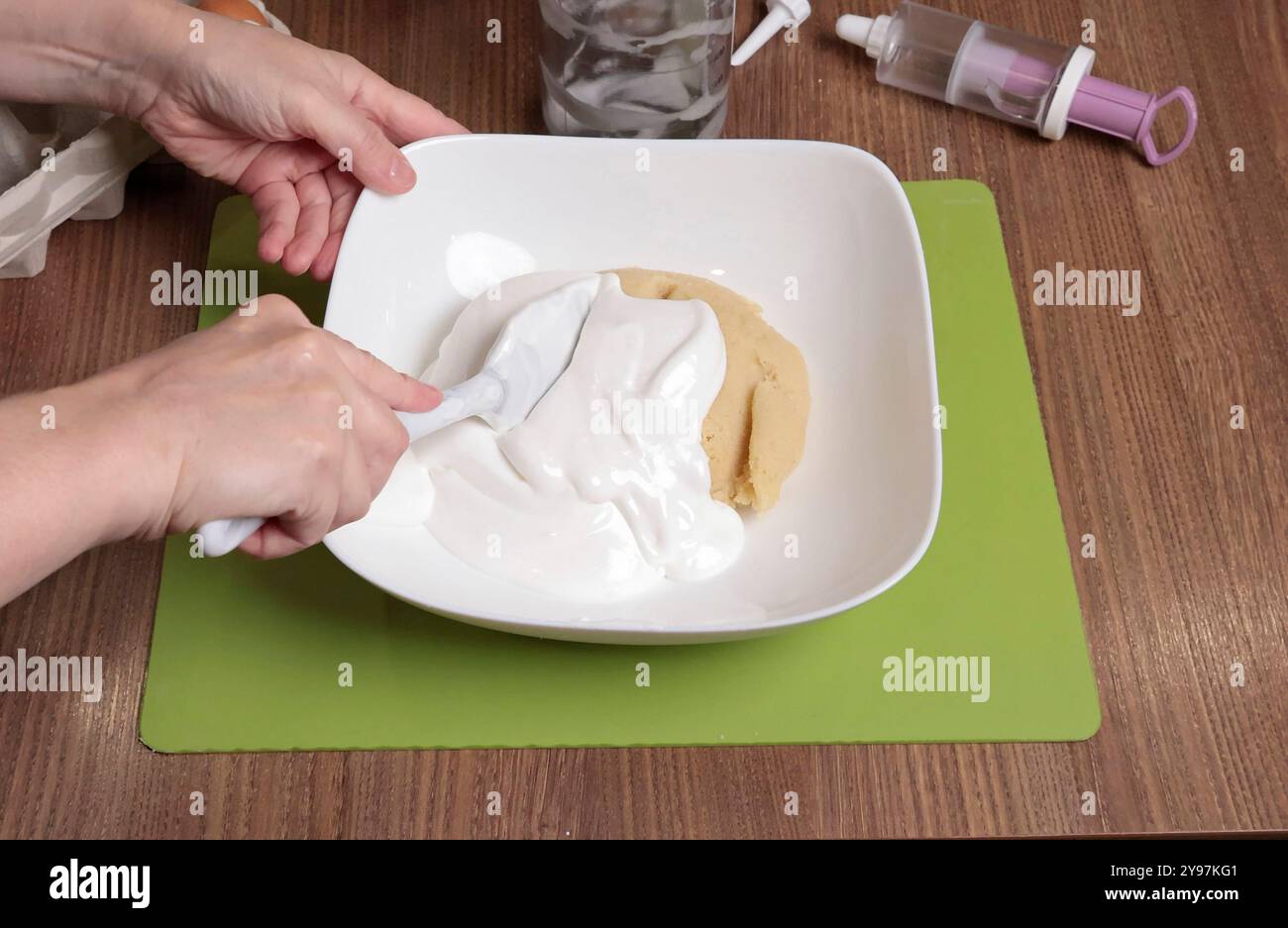 Processo di preparazione dell'impasto. Donna mescolare nel recipiente lo zucchero a velo, la farina di mandorle e l'albume sbattuto con una spatola al silicone. Preparare i macaron a casa. Chiudi Foto Stock