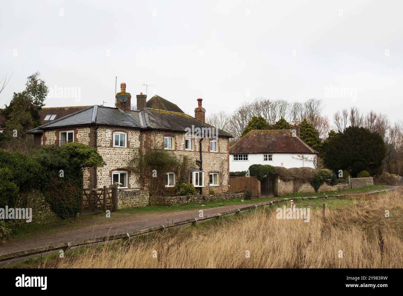Un affascinante cottage in pietra focaia e mattoni annidato nella tranquilla campagna di Alfriston, che mostra la serena bellezza della vita rurale inglese. Foto Stock