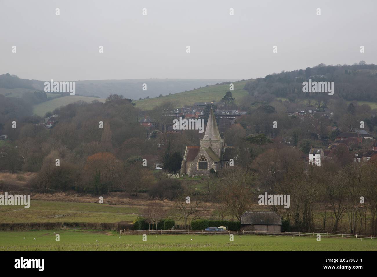 Chiesa storica ad Alfriston, nell'East Sussex, annidata in una valle panoramica dell'inverno con dolci colline e vedute rustiche della campagna. Foto Stock