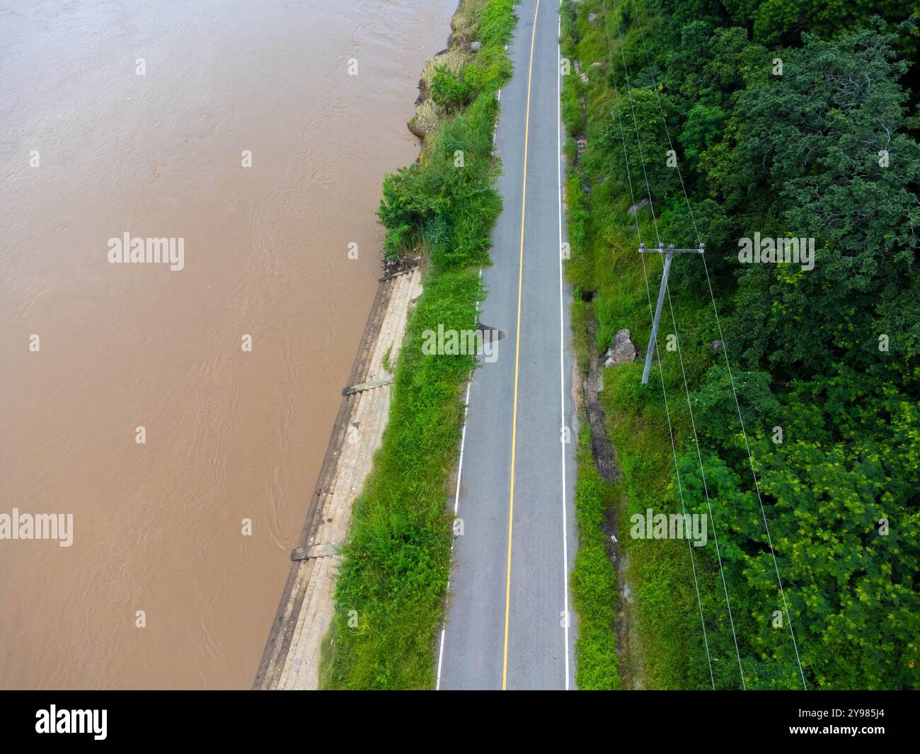 Strada asfaltata lungo il fiume su uno sfondo verde naturale. Foto Stock