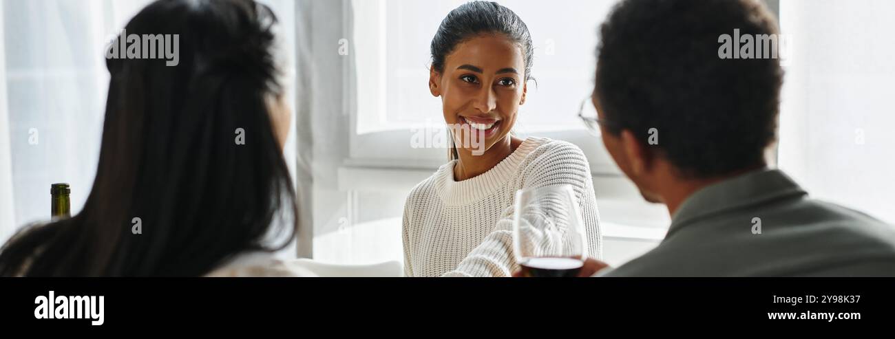 Gli amici si riuniscono intorno a un tavolo, condividendo risate e cibo durante le celebrazioni del Ringraziamento. Foto Stock