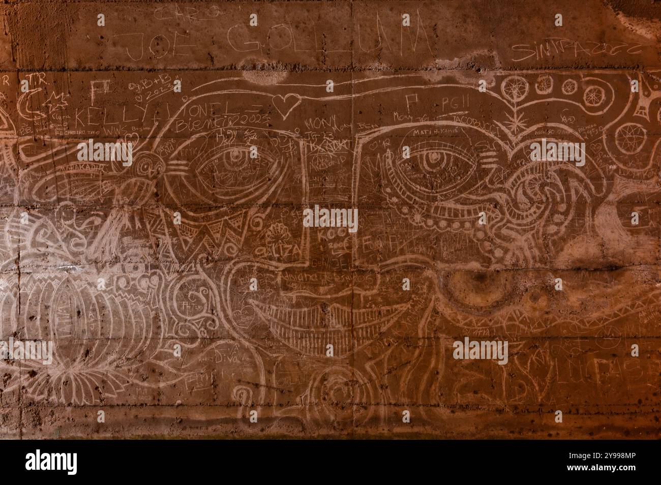 l'arte dei graffiti ntricati copre le pareti del tunnel, mescolando facce e motivi astratti nel cemento robusto Foto Stock