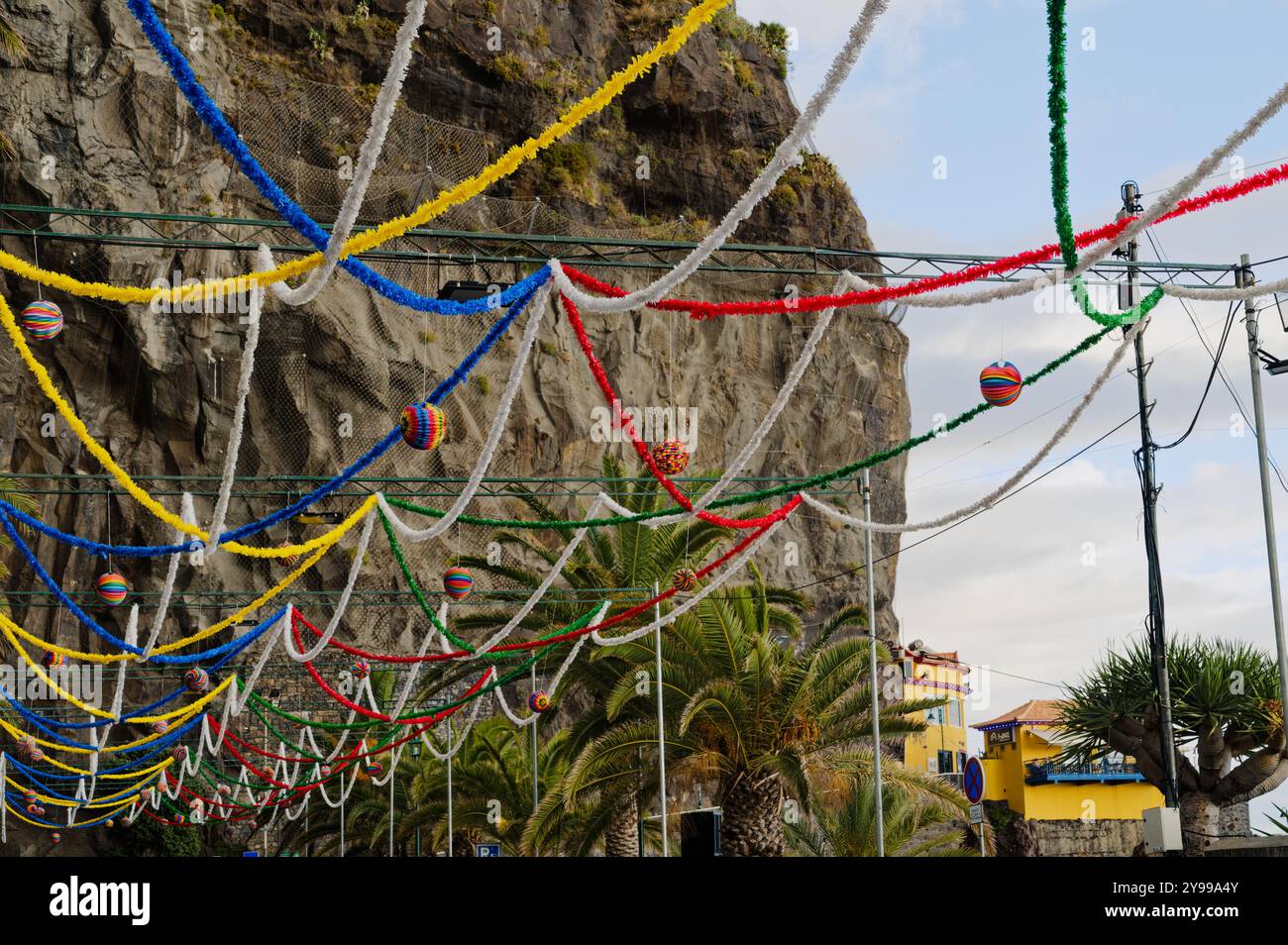 Le colorate decorazioni dei festival sono appese in aria sullo sfondo di scogliere e palme a ponta do sol Foto Stock