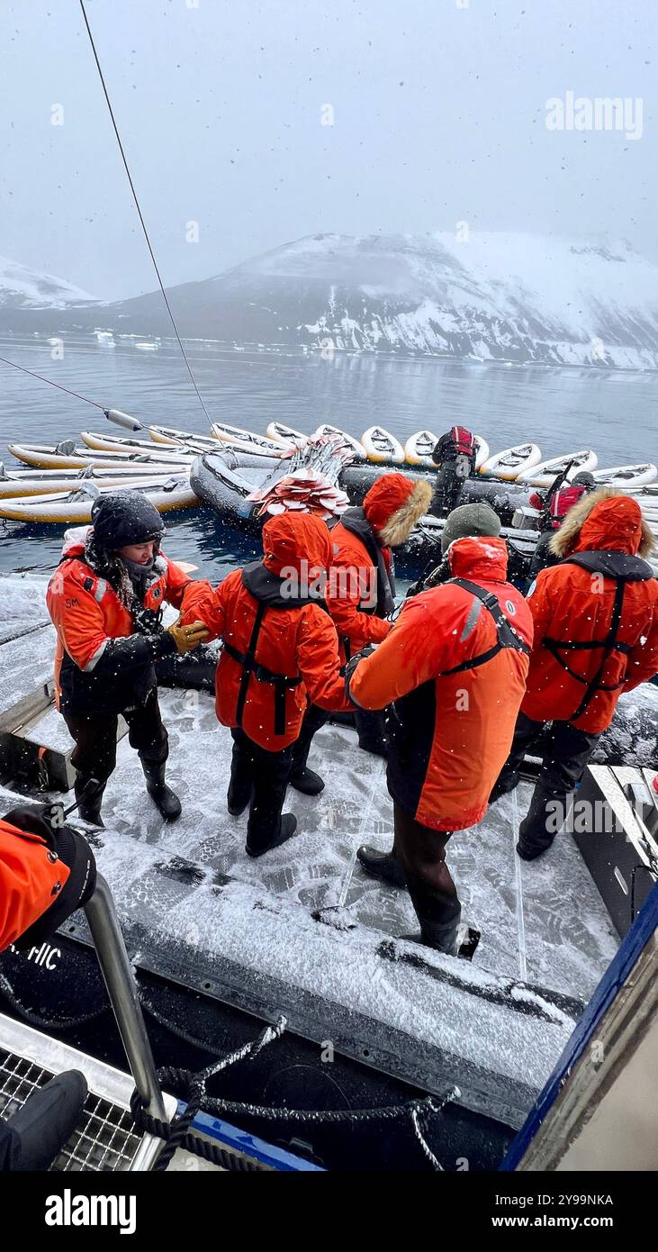 I passeggeri della Nat Geo Endurance si preparano a scendere sulla costa innevata della penisola di Trinity, Antartide, durante una nevicata leggera - Immagine stock catturata con smartphone