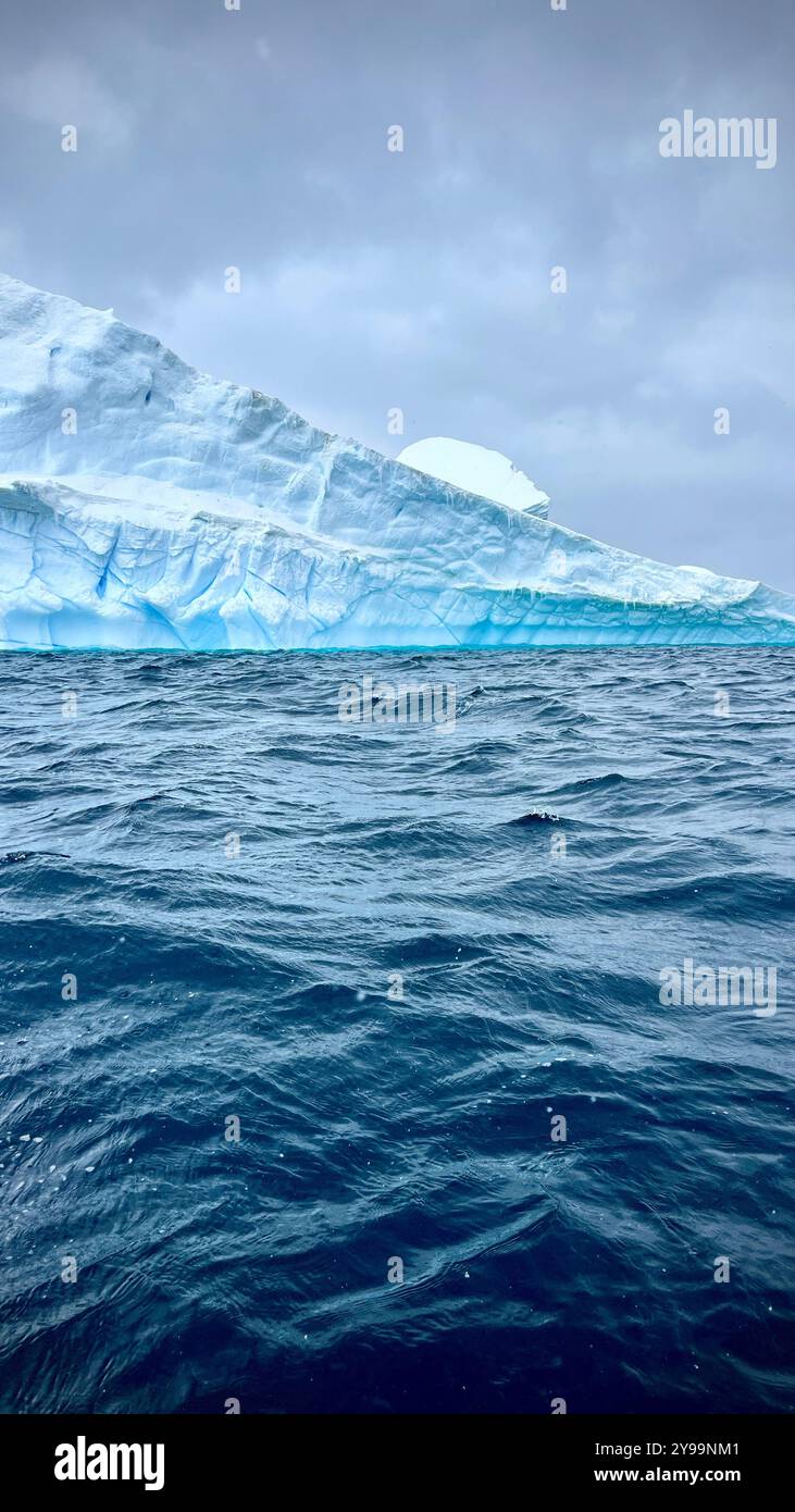Un iceberg torreggiante dalle profonde sfumature blu sorge dalle acque instabili dell'Oceano meridionale in Antartide - Immagine stock catturata con smartphone