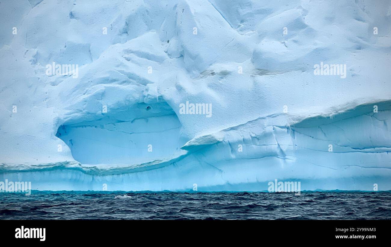 Un primo piano degli impressionanti strati blu di un iceberg che si innalzano dalle acque scure dell'Oceano meridionale in Antartide - Immagine stock catturata con smartphone