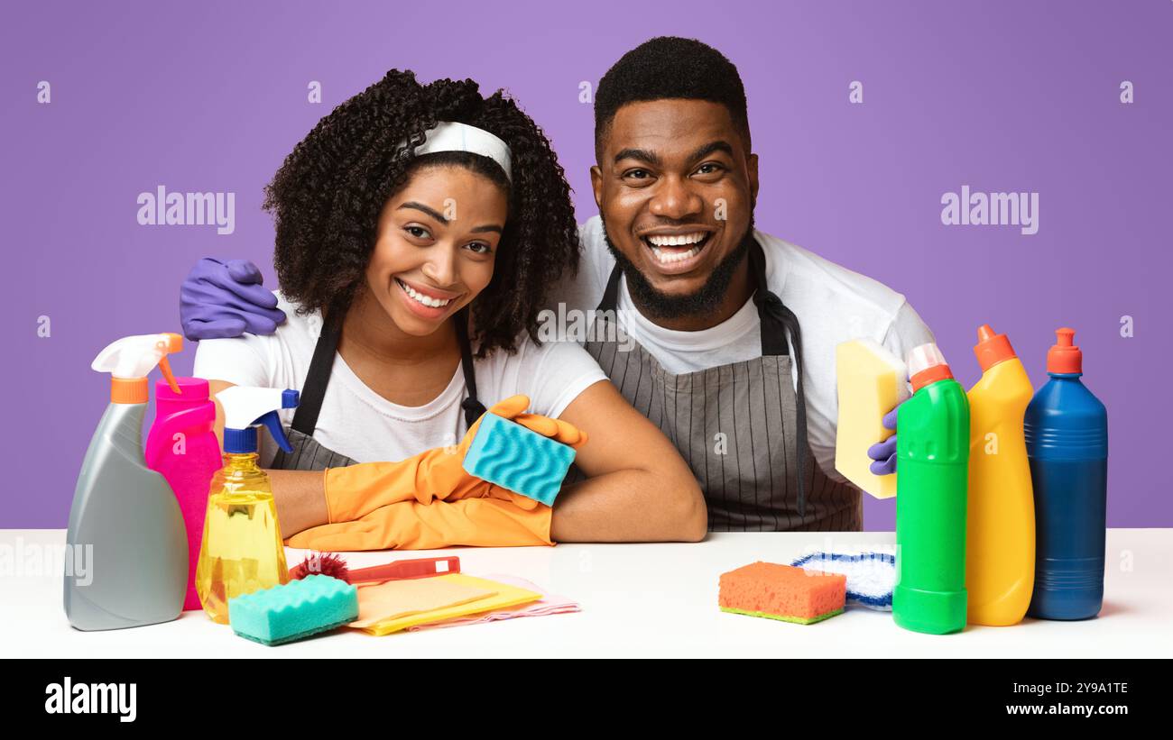 Pulizia della molla. Coppia nera seduta al tavolo con molti detergenti Foto Stock