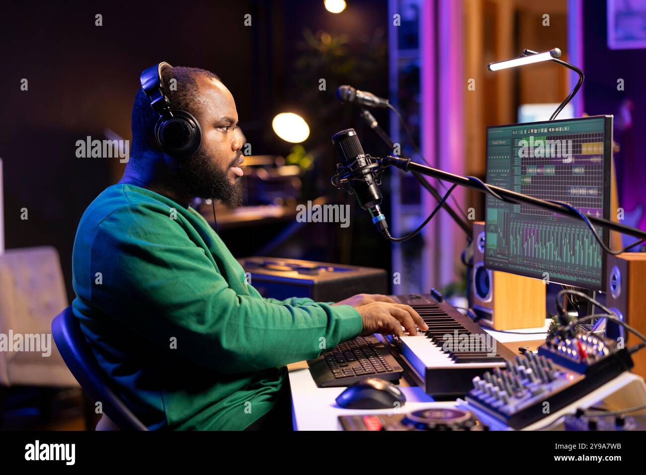 Giovane cantautore che suona il pianoforte e canta al microfono, registra la sua nuova musica e mixa i brani su un software digitale. Musicista compositore che produce colonne sonore con attrezzature moderne. Foto Stock