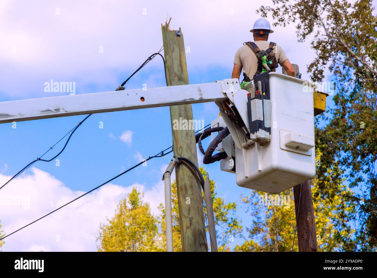 Le riparazioni dei pali di alimentazione vengono eseguite dopo l'uragano utilizzando la benna montata sulla torre idraulica montata sul dumper. Foto Stock