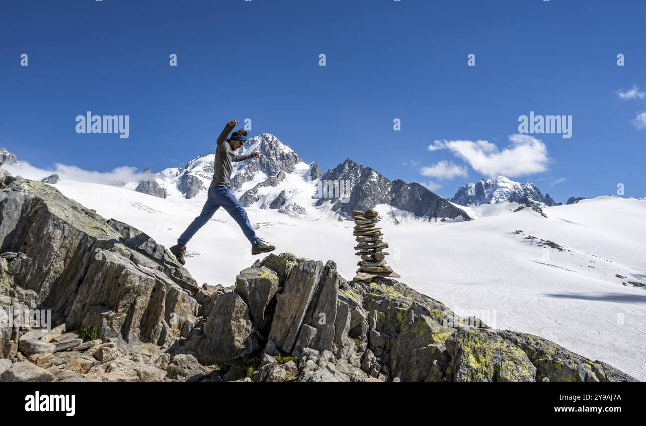 Alpinista che salta da pietra a pietra, cairn, paesaggio di alta montagna, Glacier du Tour, ghiacciaio e vetta della montagna, cima dell'Aiguille de Char Foto Stock