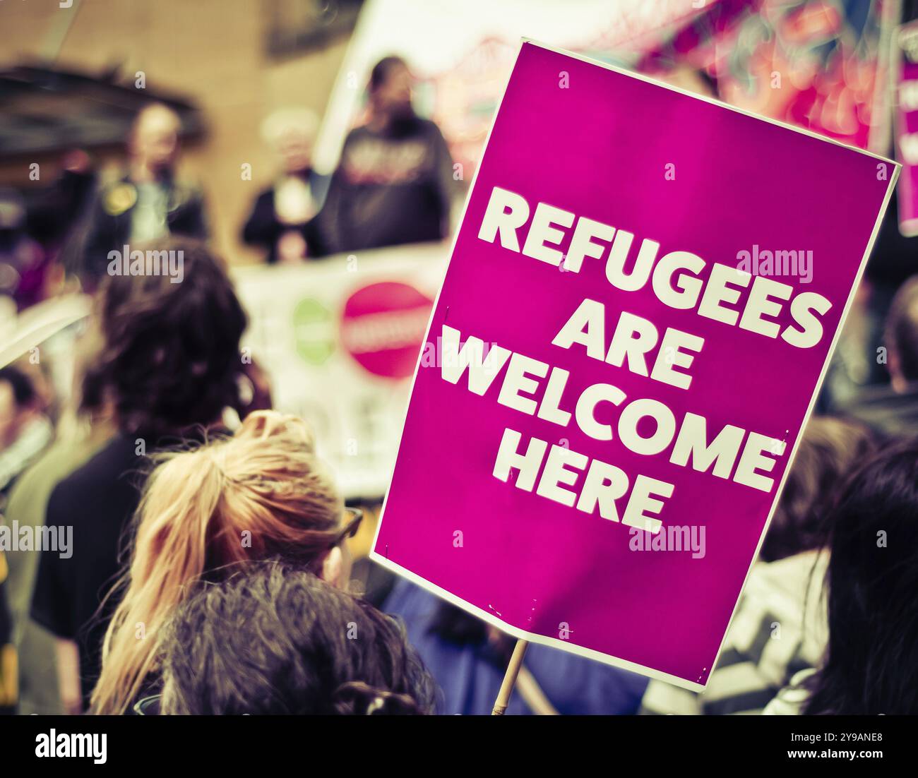 Strada trafficata marcia di protesta con un cartello che diceva i rifugiati sono benvenuti Heren Foto Stock