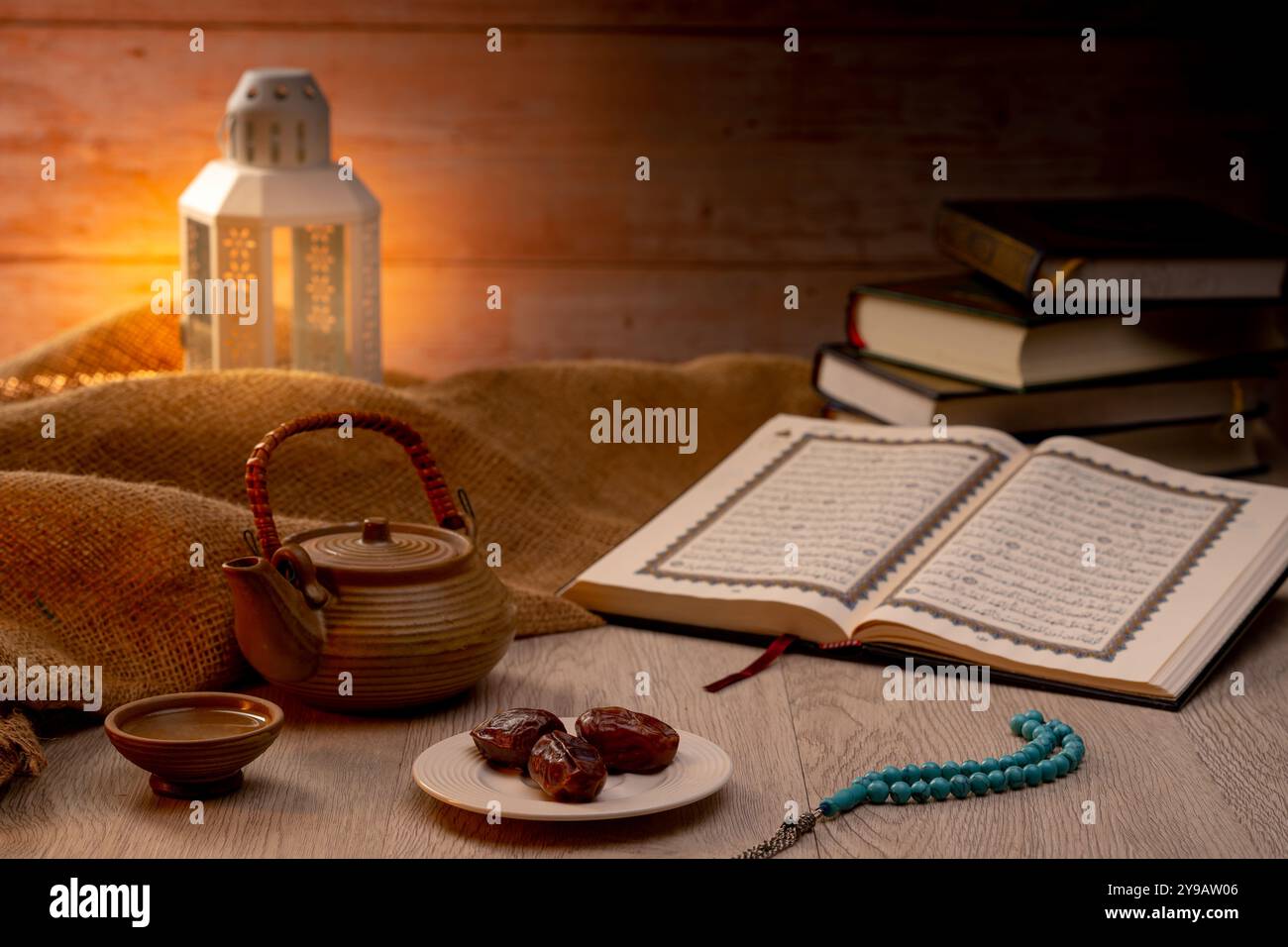 Molte palme di datteri sono su ciotole, piatti, una tazza d'acqua, e Corano, una lampada in stile Islami sui tavoli di legno, per aspettare il tempo di Iftar, con il co Foto Stock