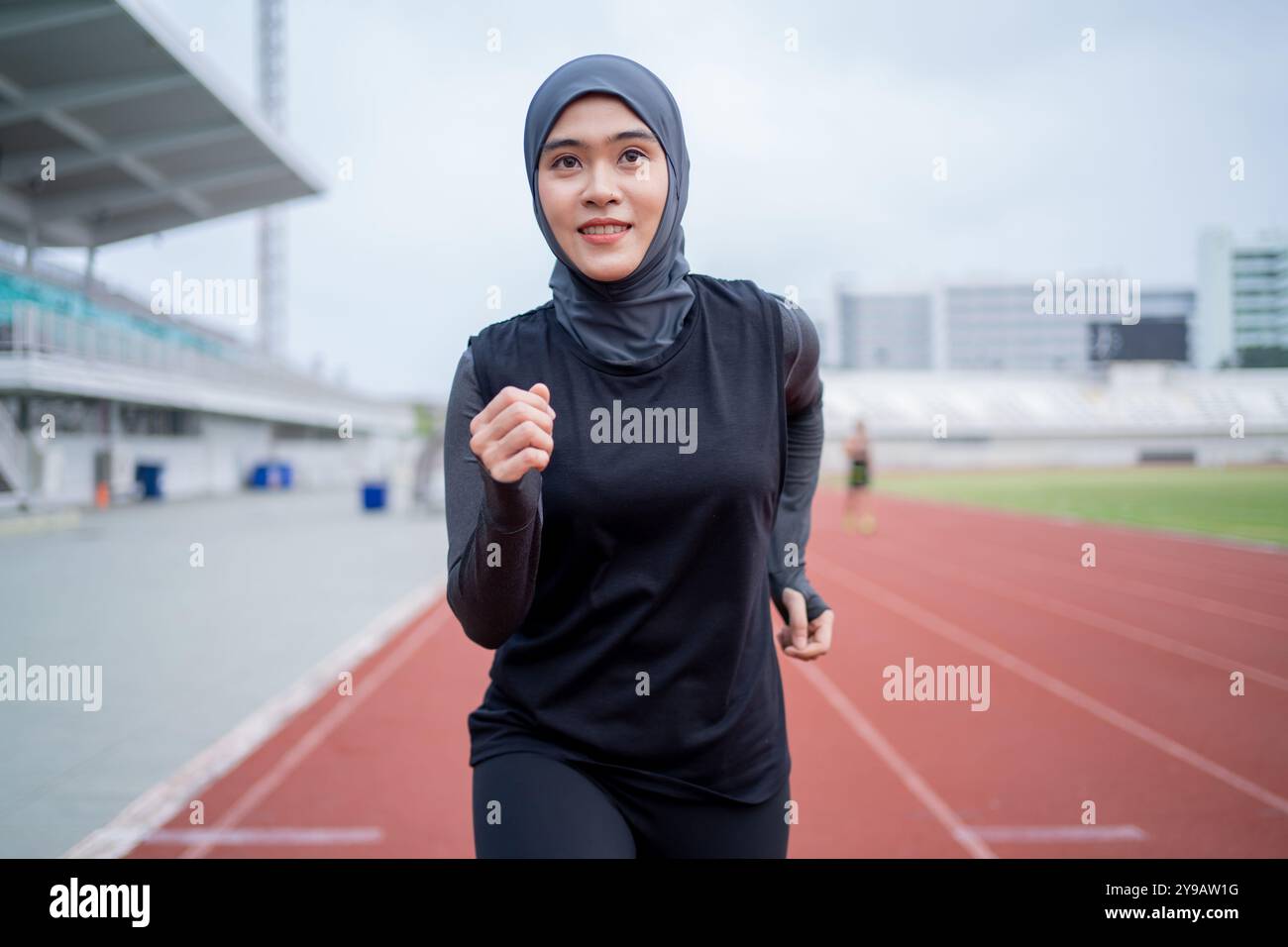 Una giovane donna musulmana asiatica che indossa un hijab nero si sta esercitando e correndo in uno stadio all'aperto la mattina. Concetto di donna musulmana moderna, musulmana W Foto Stock