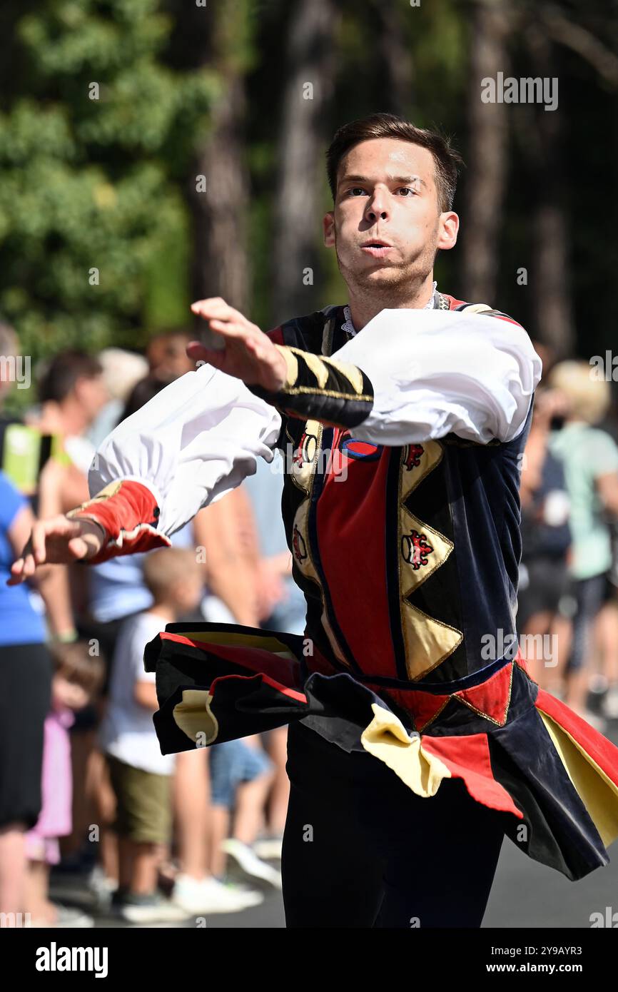 Badacsony, Lago Balaton, Ungheria - 8 settembre 2024: Festa della vendemmia del vino sfilata di strada, giovane che lancia e cattura la bandiera Foto Stock