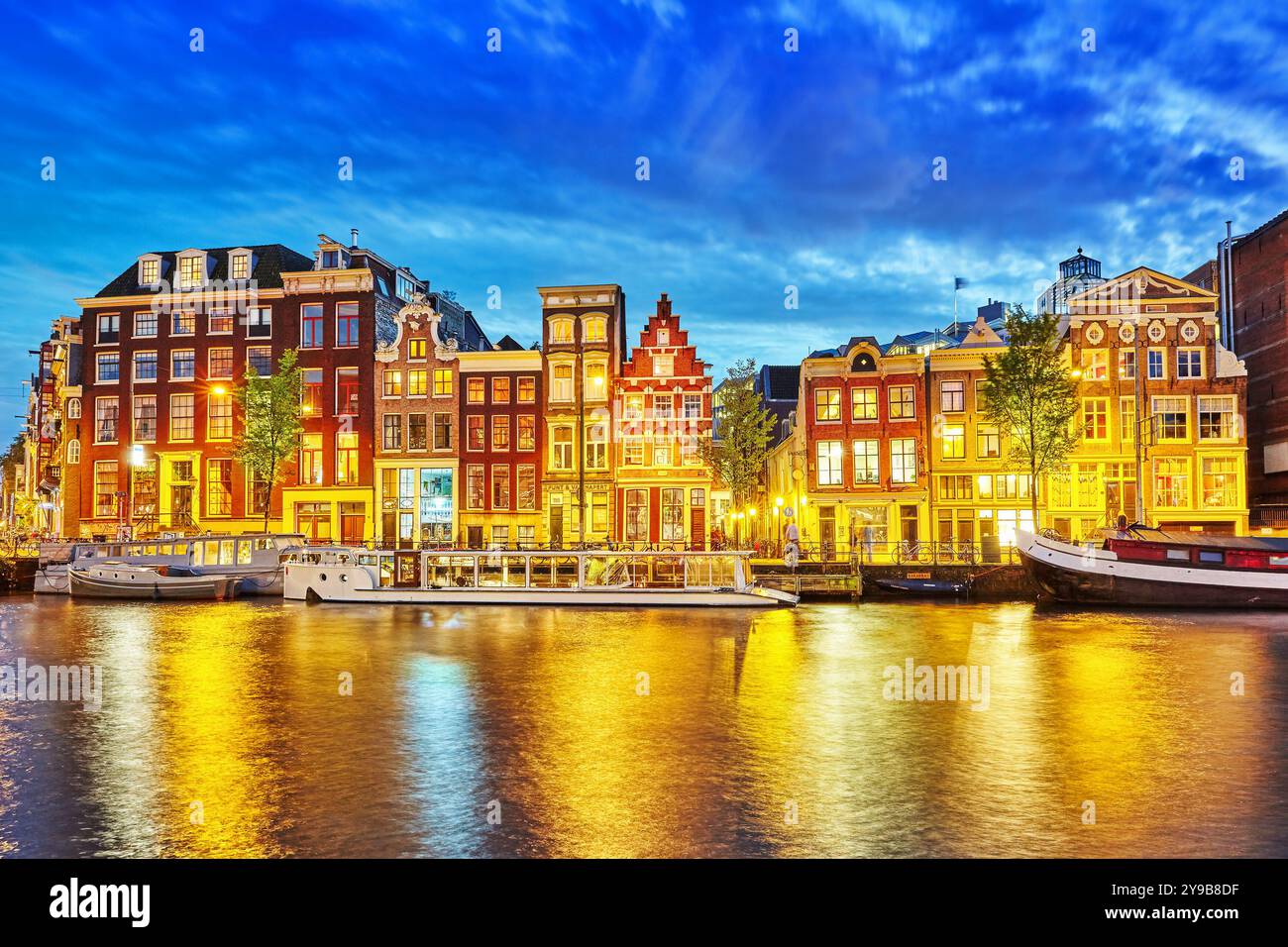 Famoso fiume Amstel e vista notturna della bellissima città di Amsterdam. Paesi Bassi Foto Stock