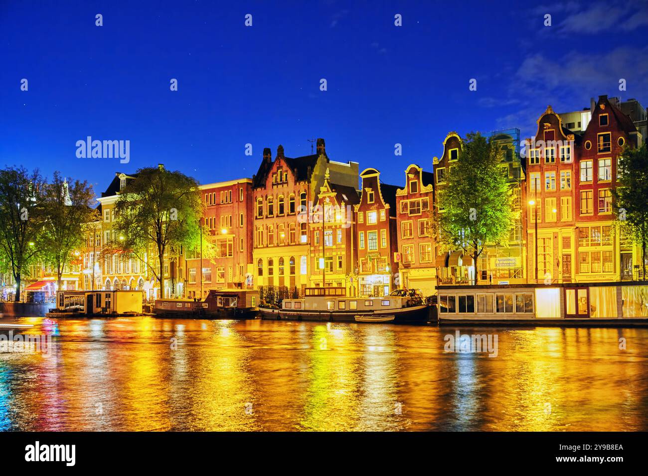 Famoso fiume Amstel e vista notturna della bellissima città di Amsterdam. Paesi Bassi Foto Stock