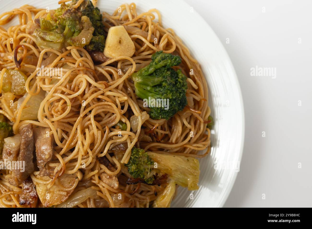 Spaghetti all'uovo in stile Hong Kong fritti in padella su sfondo bianco Foto Stock