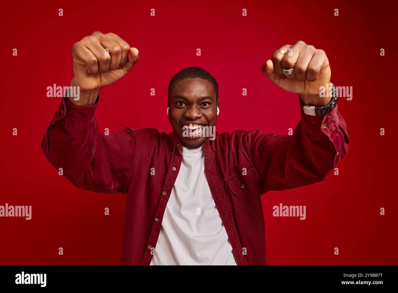 ritratto di un uomo afroamericano emotivo che si rallegra con le mani allungate alla macchina fotografica isolata su sfondo rosso, ritratto in studio Foto Stock