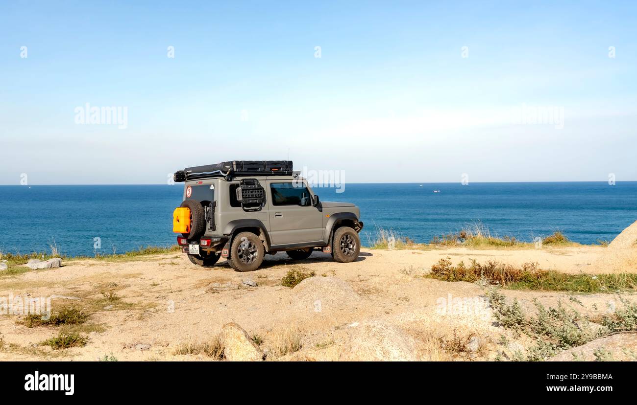 MUI Dien, Tuy Hoa City, provincia di Phu Yen, Vietnam - 8 settembre 2024: Il Suzuki Jimny si sta arenando sulla scogliera con il vasto oceano da un lato. La f Foto Stock