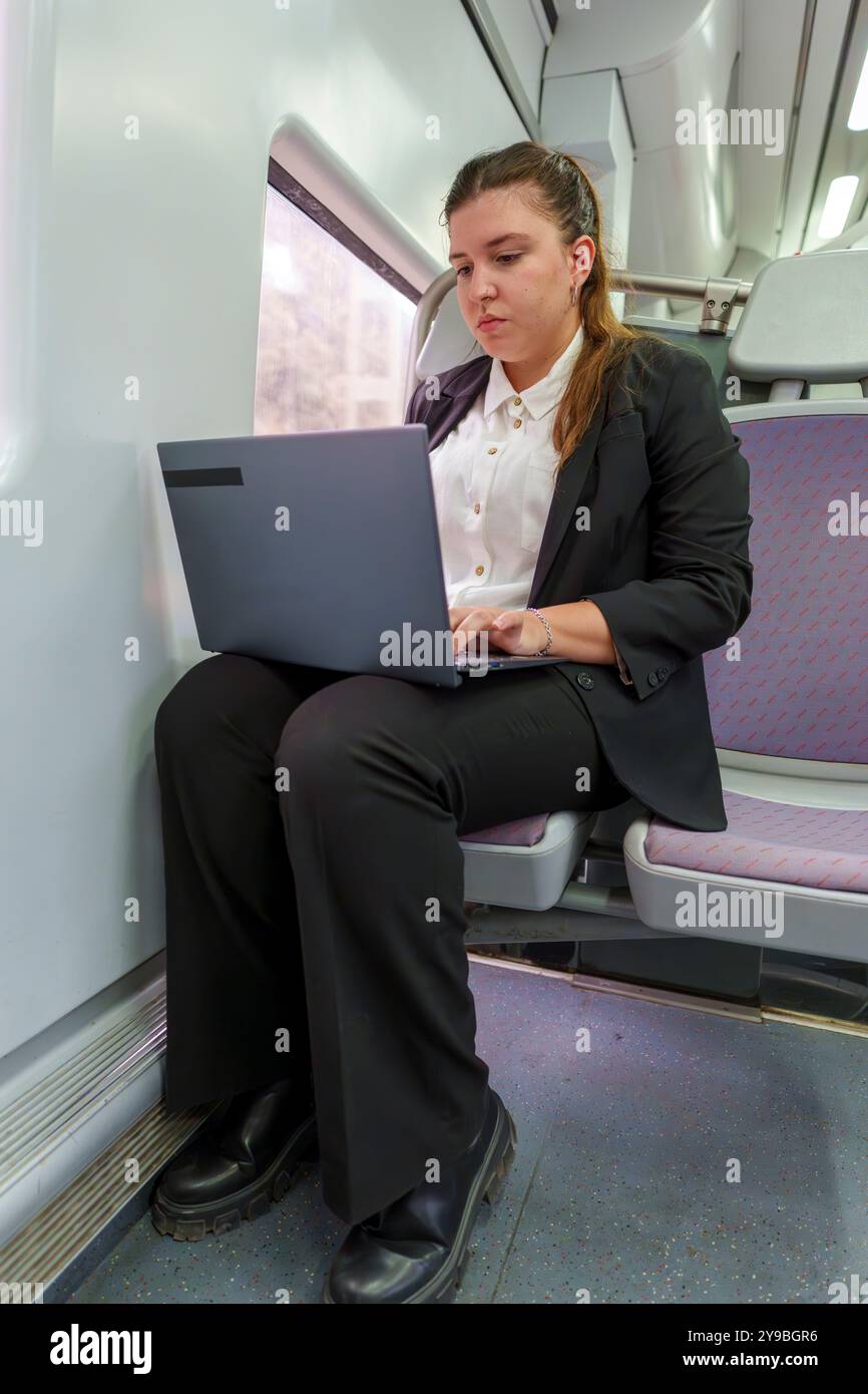 Giovane donna d'affari che lavora su un notebook mentre viaggia in treno Foto Stock