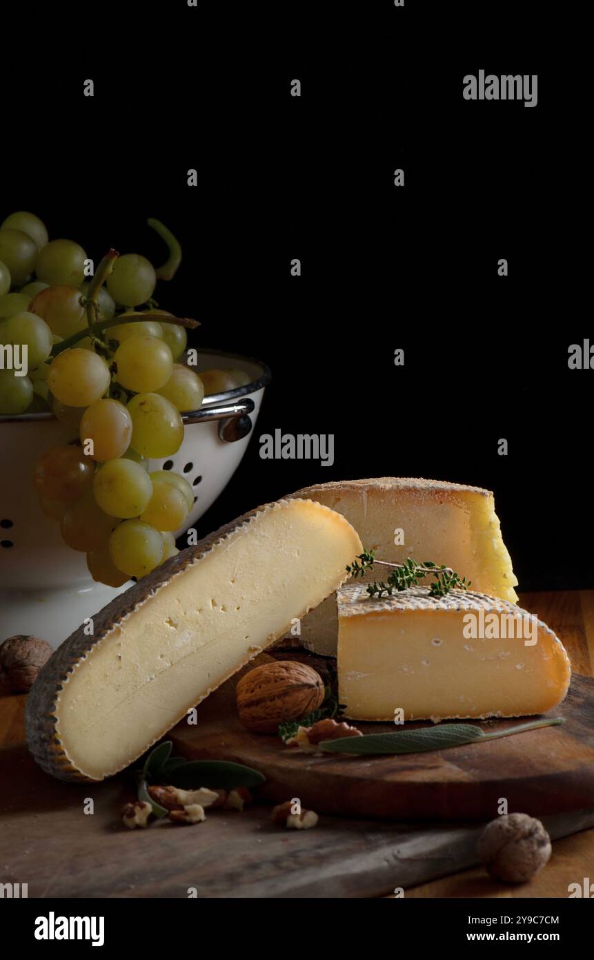 Formaggio verde bulgaro su sfondo nero con un mucchio di uva, noci ed erbe aromatiche Foto Stock