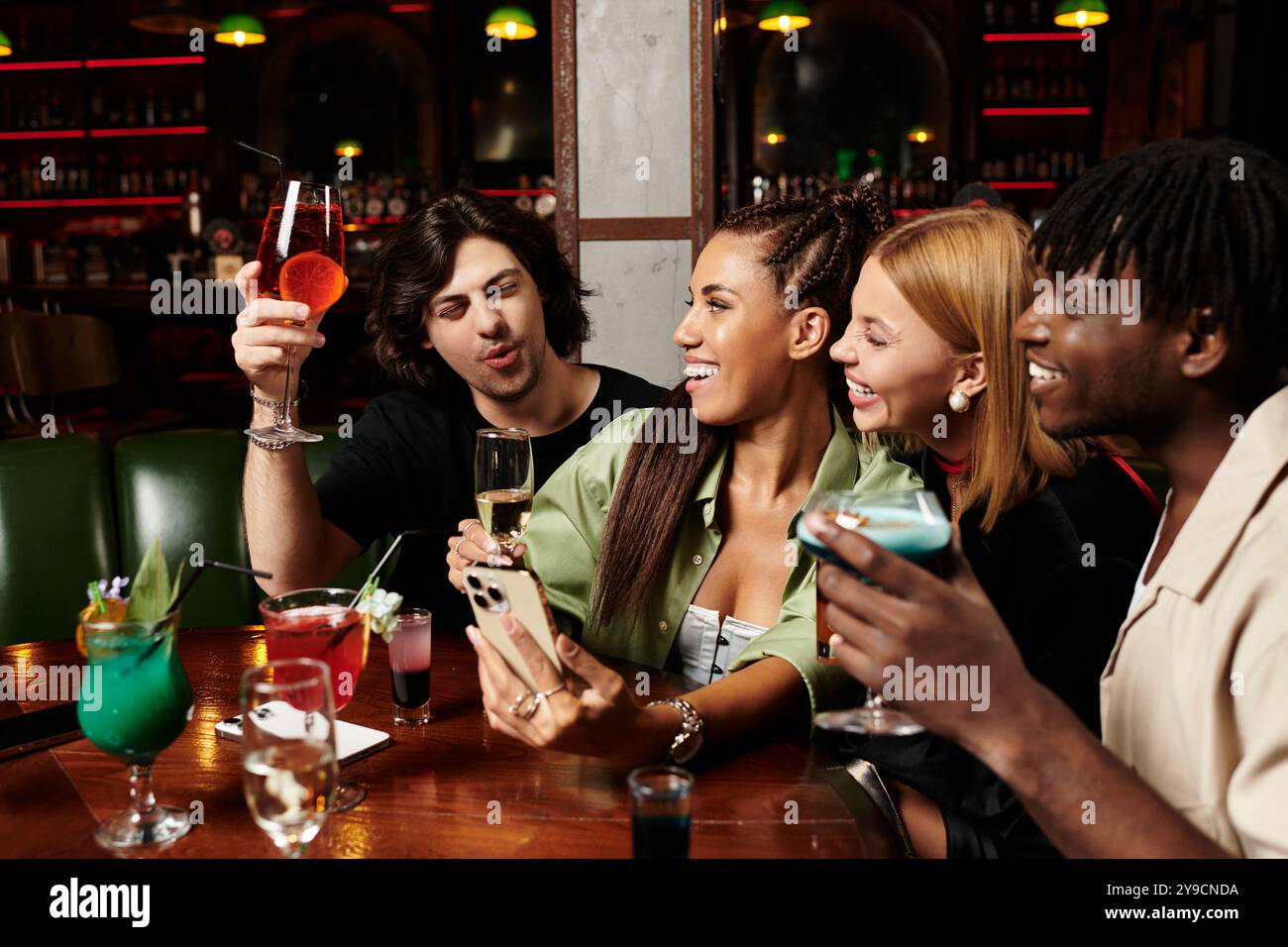 I colleghi trascorrono una serata vivace insieme, condividendo drink e risate durante una riunione aziendale. Foto Stock