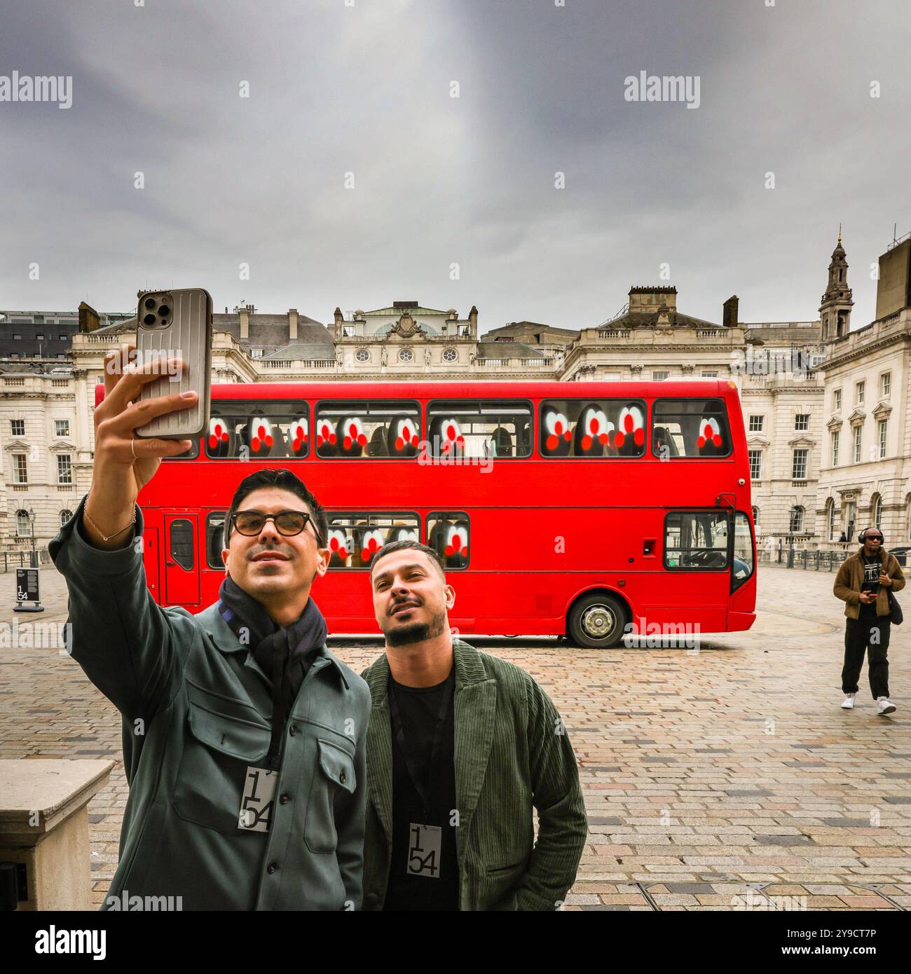 Londra, Regno Unito. 10 ottobre 2024. I visitatori scattano foto con l'installazione, che originariamente doveva avere due autobus, non uno. L'artista non era presente come previsto. Un'installazione monumentale composta da un autobus a grandezza naturale di Londra è stata inaugurata nel cortile di Somerset House dall'artista Slawn. Gli autobus a due piani dell'artista anglo-nigeriano Slawn esplorano l'accessibilità e i collegamenti sociali. 1-54 Contemporary African Art Fair celebra la sua dodicesima edizione a Somerset House con l'installazione speciale. Oltre 60 gallerie e 160 artisti africani e della diaspora sono in mostra al Foto Stock